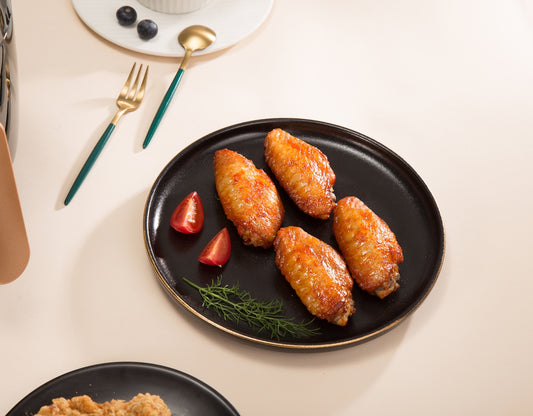 fried food on black ceramic plate beside silver fork and knife