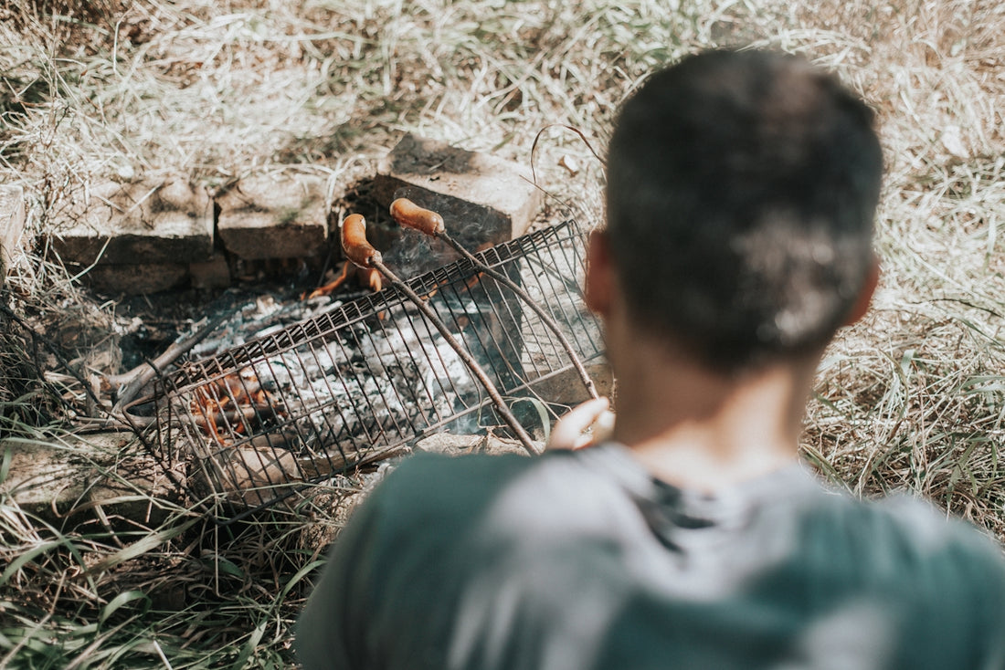 A man standing next to a fire pit in the grass