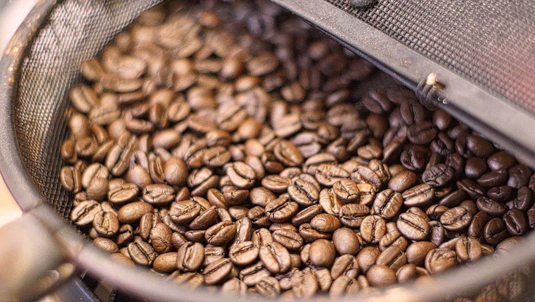 Coffee beans roasting inside a sieve.