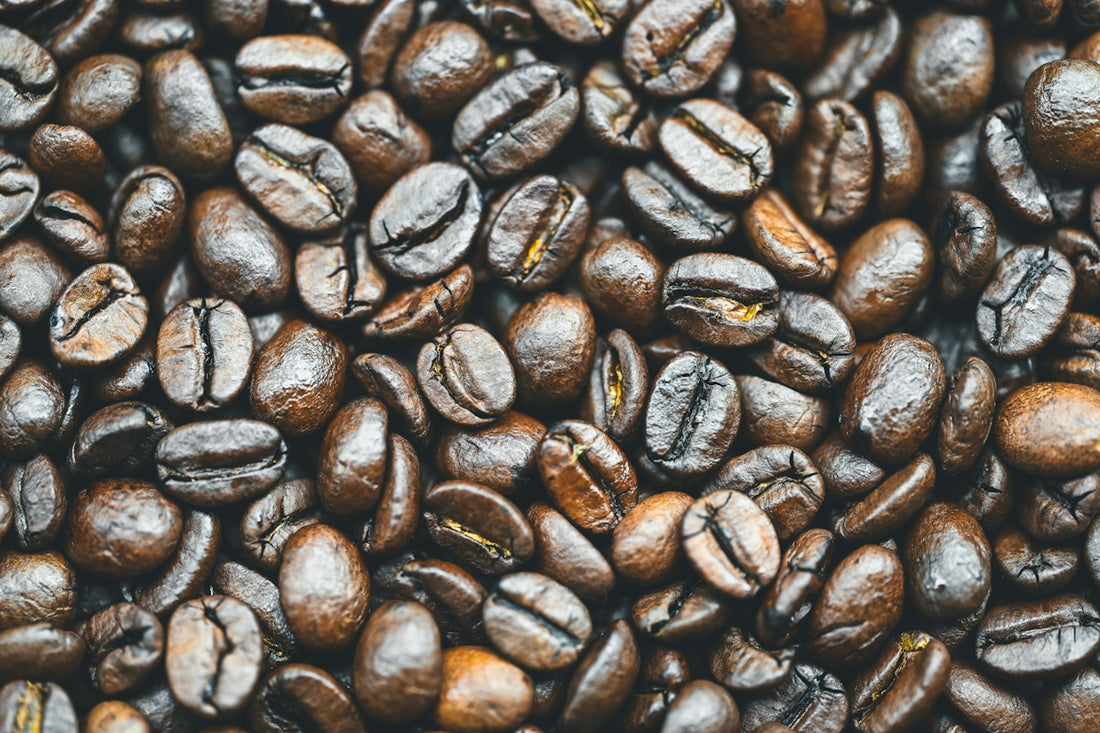 Dark roasted coffee beans scattered across a surface
